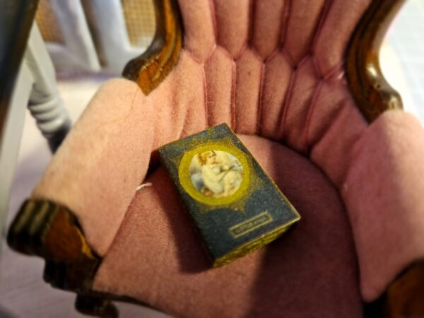 Miniature antique historical magical book sitting in an antique 12th scale chair
