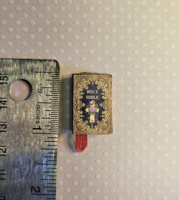 Front of miniature antique holy bible book 12th scale against steel ruler